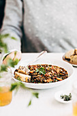 French Lentil Soup served on a table, with a woman seated