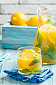Lemonade drink. Lemonade in the jug and glass with lemons and mint on the table