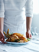 A woman serving roast chicken with thyme