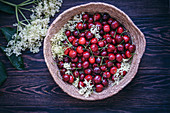 Fresh cherries and flowers in a basket on rustic wooden table