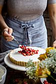 Adding fruit to the top of a mascarpone and strawberry tart