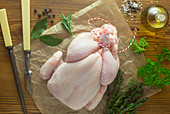 A whole raw chicken with ingredients on baking paper