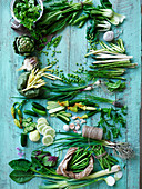 Grünes Gemüse und Kräuter auf blauem Holzuntergrund