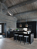 Modern, open-plan kitchen with black cabinets in grey log cabin
