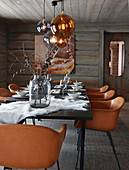 Cognac-brown chairs around set dining table in log cabin