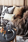 Sofa mit Fell und Kissen davor Couchtisch mit Herbstdekoration