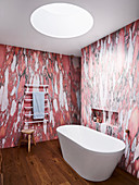 Frei stehende Badewanne und Handtuchtrockner im Badezimmer mit Tapete in Rotmarmor-Effekt