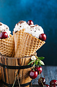 Vanilla ice cream, chocolate sprinkles and cherries in ice cream cones