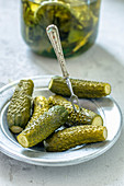 A plate of gherkins in front of a gherkin jar