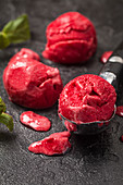 Raspberry red ice cream balls in ice cream spoon with mint