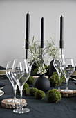 Wine glasses on wooden coasters and handmade moss balls on set table