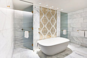 Marble tiles and ornate pattern on wall above bathtub in luxurious bathroom