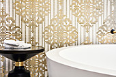 Ornate pattern of gold and white mosaic tiles behind bathtub