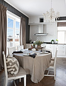 Dining table with linen tablecloth and chairs in bright kitchen