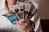 Elderly woman holding British banknotes