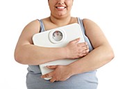 Overweight woman holding weighing scales