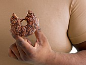 Overweight man holding a doughnut with a missing bite