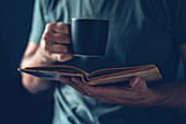 Man reading book and drinking coffee
