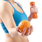 Woman holding orange and hand weight