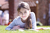 Girl lying on grass reading