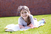 Girl lying on grass reading