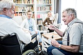 Senior man in wheelchair talking to friend