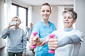 Woman holding hand weights with physiotherapist