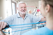 Senior man using resistance band in exercise class
