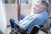 Senior man in wheelchair by window