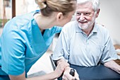 Senior man using rollator with carer assisting