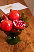 Whole and halved pomegranates in glass bowl