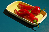 Three red chili peppers in a yellow bowl