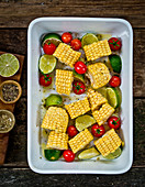 Roasted corn on the cob with cherry tomatoes and limes