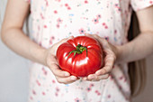 A girl holding a large tomato