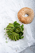 A sesame bagel with almond cheese, avocado, cucumber and fresh herbs (vegan)