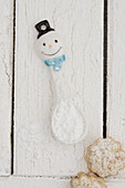 A snowman spoon with powdered sugar and cookies