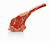A raw tomahawk beef steak against a white background