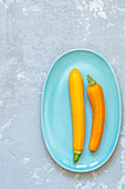 Two yellow zucchini on a pale blue plate
