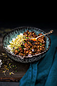 Crispy beef stir fry with aubergine and mushrooms served in a bowl over rice and spicy chilli sauce