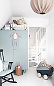 Rocking chair, dolls' pram and grey wardrobe in white nursery