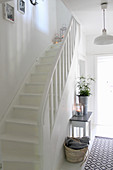 Console table and runner next to staircase in white hallway