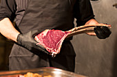 A man holding a raw tomahawk steak