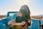Mutter umarmt ihren Sohn auf der Ladefläche eines Pick-ups (Wüstenlandschaft, Arizona, USA)