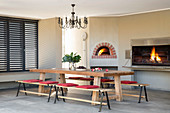 Wooden table with benches, pizza oven and barbecue in dining area