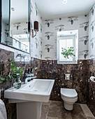 Wallpaper with savanna pattern and dark marble wall tiles in guest toilet