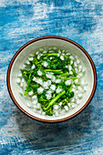 Blanched broccoli in ice water on a blue old background