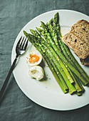 Cooked asparagus with soft-boiled egg, grilled bread and herbs