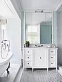 Wall mirror over white vanity and free-standing bathtub in elegant bathroom