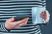 Woman with smartphone and mug