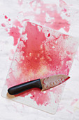 Schneidebrett und Messer mit Rote-Bete-Saftflecken